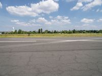 an airport runway with the sky and clouds in the background, on a summer day