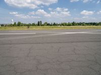 an airport runway with the sky and clouds in the background, on a summer day