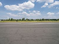 an airport runway with the sky and clouds in the background, on a summer day