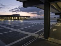 view of an empty parking lot from inside an airport terminal at night, with buildings in the background