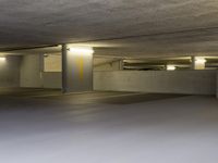 a parking garage with lights glowing from the windows and empty spaces inside a building with concrete walls