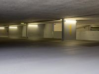 a parking garage with lights glowing from the windows and empty spaces inside a building with concrete walls