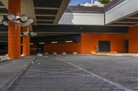 there is an empty parking area next to a building with many lights and orange colored brickwork