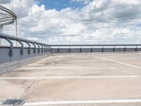 an empty parking lot under a cloudy blue sky with clouds in the background by the bridge