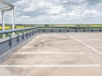 an empty parking lot under a cloudy blue sky with clouds in the background by the bridge