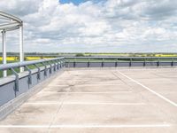 an empty parking lot under a cloudy blue sky with clouds in the background by the bridge