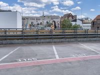 an empty parking lot with the words paris written on the pavement in white paint with a painted mural in background