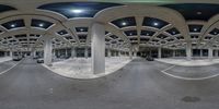 a wide view of a parking lot with multiple columns inside it with a yellow light in the background