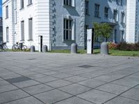 a white and grey building on a street corner with sidewalk barriers for bike lanes and bicycles