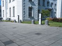 a white and grey building on a street corner with sidewalk barriers for bike lanes and bicycles