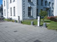 a white and grey building on a street corner with sidewalk barriers for bike lanes and bicycles