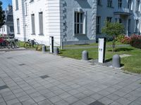 a white and grey building on a street corner with sidewalk barriers for bike lanes and bicycles