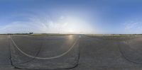 the image has an oval panoramic view of a parking lot with a runway