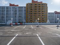 an empty parking lot filled with parking cones and buildings in the background with an orange stripe on the ground