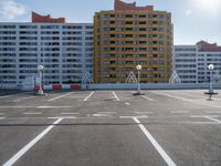 an empty parking lot filled with parking cones and buildings in the background with an orange stripe on the ground