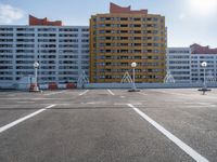 an empty parking lot filled with parking cones and buildings in the background with an orange stripe on the ground