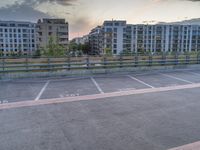 an empty parking lot near some tall buildings with word written on it at sunset in front of the sun