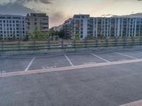 an empty parking lot near some tall buildings with word written on it at sunset in front of the sun