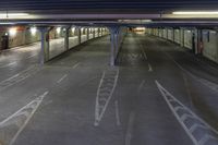 an empty street in the middle of a tunnel at night time, with an empty train station in the background