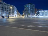 two people in the middle of the street crossing with some street lights on at night