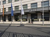 a bus is on the street next to many flags in front of a building on the road