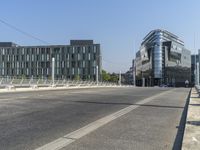 an empty street next to a building on the left and an office on the right