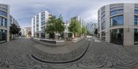 several large buildings in the background of a circle like panorama camera system, the lens is out on a cobblestone street