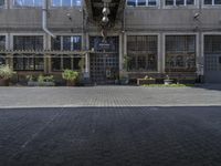 a square brick courtyard area and many windows and benches in a large building with two open windows