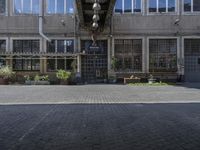 a square brick courtyard area and many windows and benches in a large building with two open windows