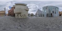 an spherical panorama of a wide open brick road and surrounding buildings with circular designs on it