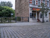 a small dog walking past a stone path outside a store front, which has a sign on its door