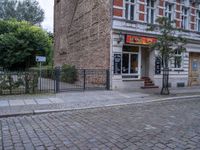 a small dog walking past a stone path outside a store front, which has a sign on its door