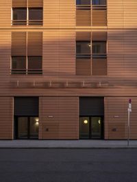 a building with four windows next to a street in front of it at dusk with light reflecting off the window