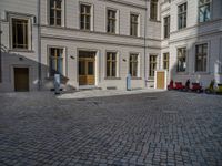 an empty parking lot with plants in the ground and on the side of the building, there is an enclosed area and windows