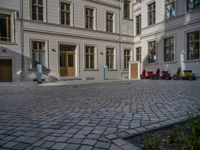 an empty parking lot with plants in the ground and on the side of the building, there is an enclosed area and windows