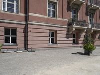 a brick walkway that leads up to several different floors and balconies in front of a pink building with wrought balcony railings