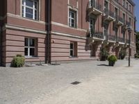 a brick walkway that leads up to several different floors and balconies in front of a pink building with wrought balcony railings