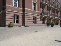 a brick walkway that leads up to several different floors and balconies in front of a pink building with wrought balcony railings