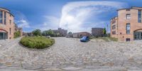 a fish lens photo taken looking down a street through a building at parked cars on a cobblestone driveway