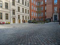 an empty parking lot with plants in the ground and on the side of the building, there is an enclosed area and windows