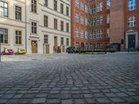 an empty parking lot with plants in the ground and on the side of the building, there is an enclosed area and windows