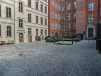 an empty parking lot with plants in the ground and on the side of the building, there is an enclosed area and windows