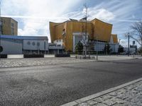 the yellow structure is behind the buildings on the street and has no pedestrians walking outside