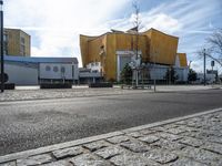 the yellow structure is behind the buildings on the street and has no pedestrians walking outside