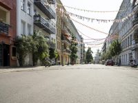 a narrow street, surrounded by multi colored hanging decorations and motorcycles parked in front of it