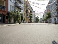 a narrow street, surrounded by multi colored hanging decorations and motorcycles parked in front of it