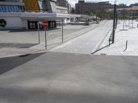 empty street with no cars on it next to parking spaces with white walls and buildings in the background