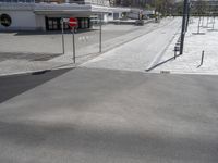 empty street with no cars on it next to parking spaces with white walls and buildings in the background