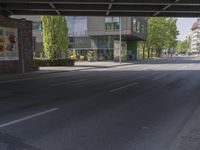 an empty street is under a bridge and houses are on the other side of it