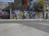 the street in front of the graffiti covered building is empty and empty, but has two rows